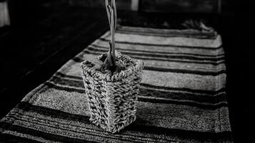 A black and white photo of a potted plant with three flowers on a striped rug in a rustic setting.