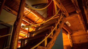 A wooden interior with a rope ladder and wooden beams.