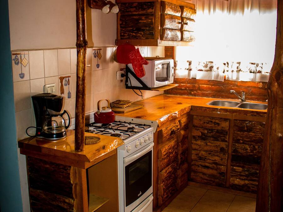 A rustic kitchen with a gas stove, microwave, and sink.