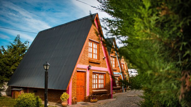 A two-story house with a steeply pitched roof, a wooden door, and a window with a wooden frame.
