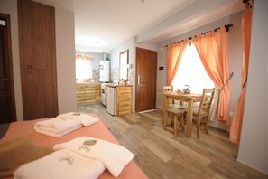 Ein Hotelzimmer mit einem Bett, einem Esstisch mit Stühlen, einer Küchenzeile und einem Badezimmer.