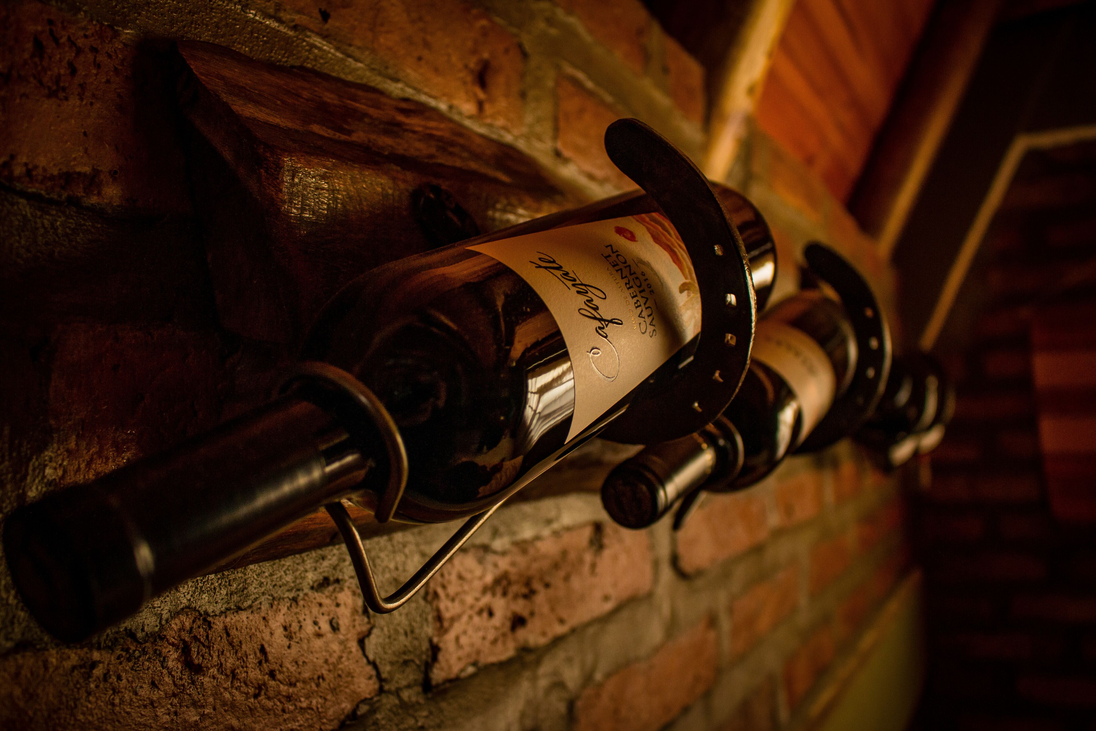 A wine bottle with a label on a brick wall.