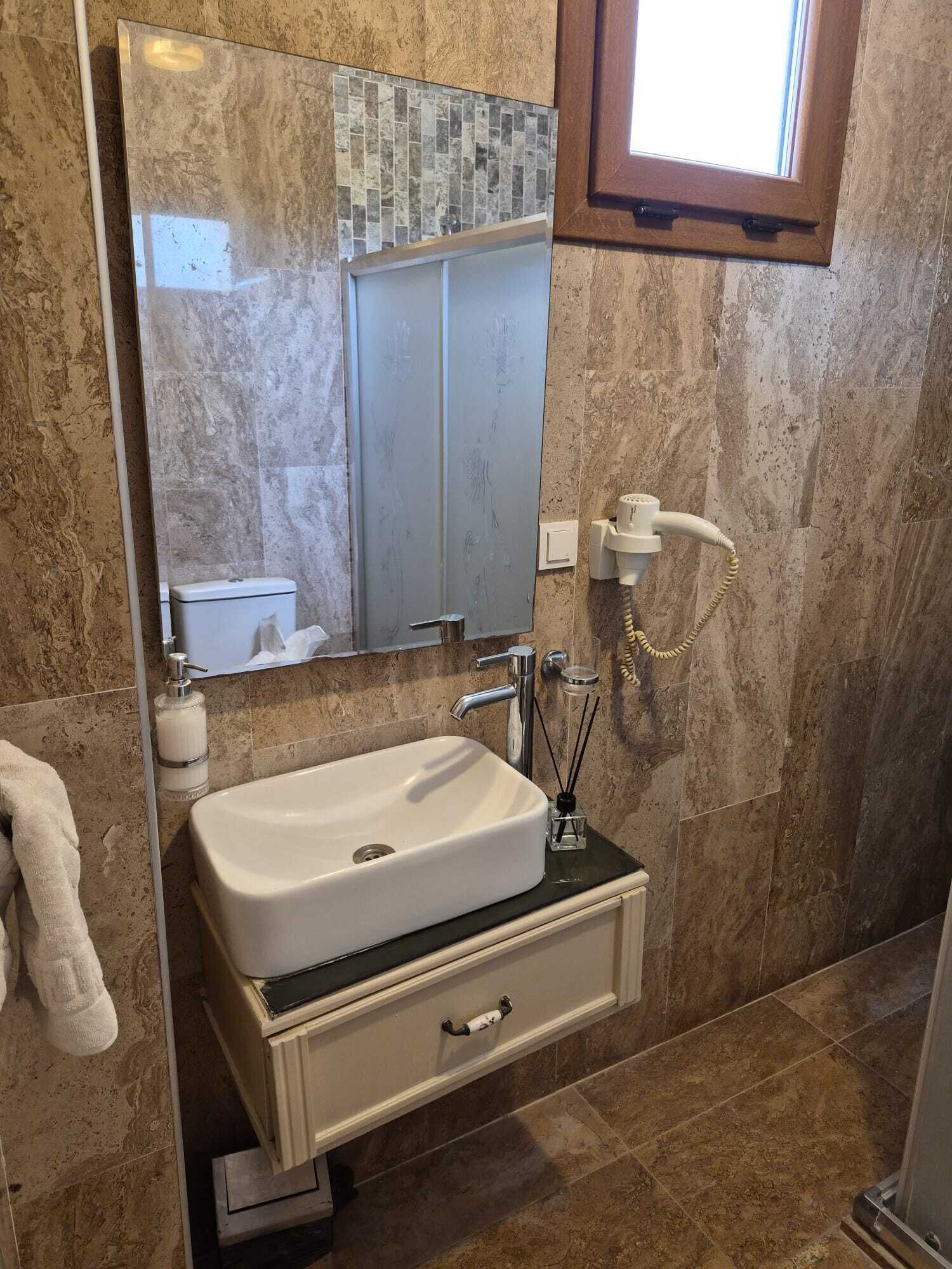 Um banheiro com pia branca, espelho, porta-toalhas e área de chuveiro.
