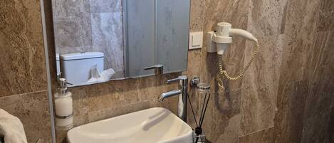 A bathroom with a white sink, a mirror, a towel rack, and a shower area.