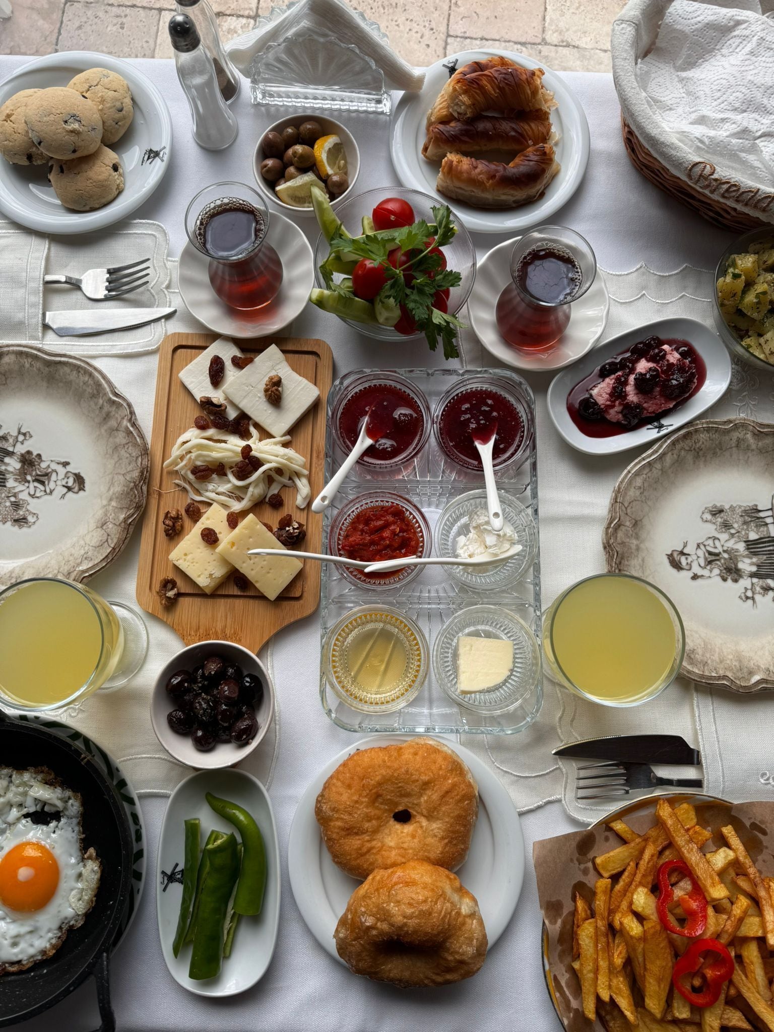 Une table dressée avec divers aliments pour le petit-déjeuner, notamment des viennoiseries, du fromage, des fruits et des condiments.