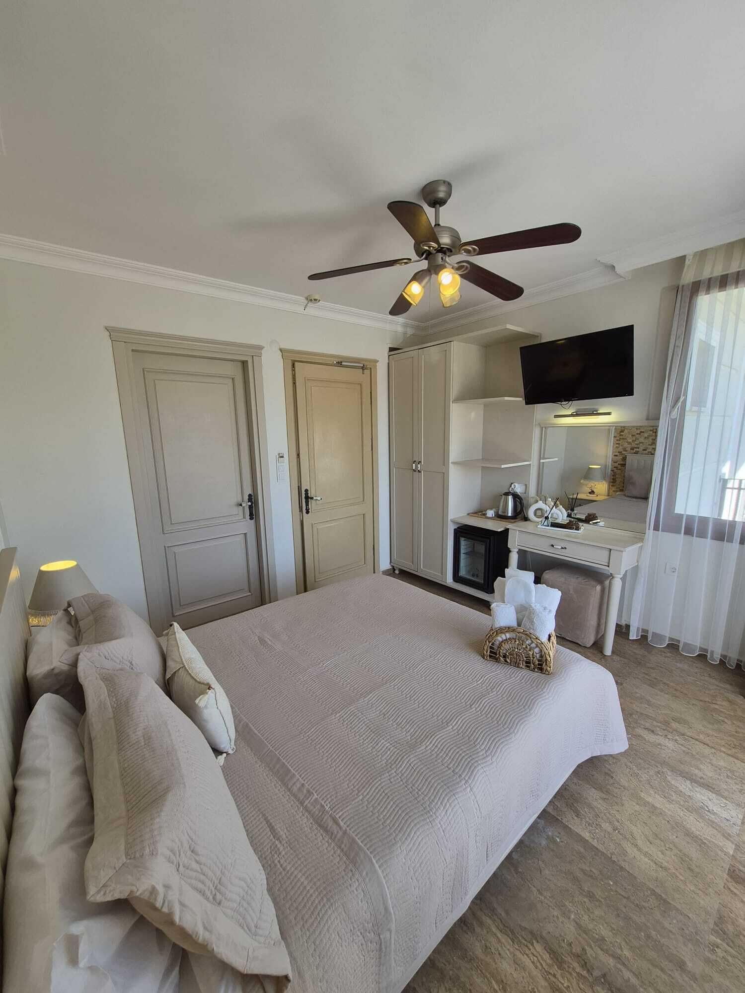 Une chambre avec un lit, un ventilateur de plafond, une télévision et un coin cuisine.