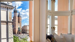 Ein Zimmer mit großem Fenster und Blick auf ein historisches Gebäude mit einem markanten Turm.