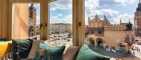 A room with a large window overlooking a historic square with buildings and a clock tower.