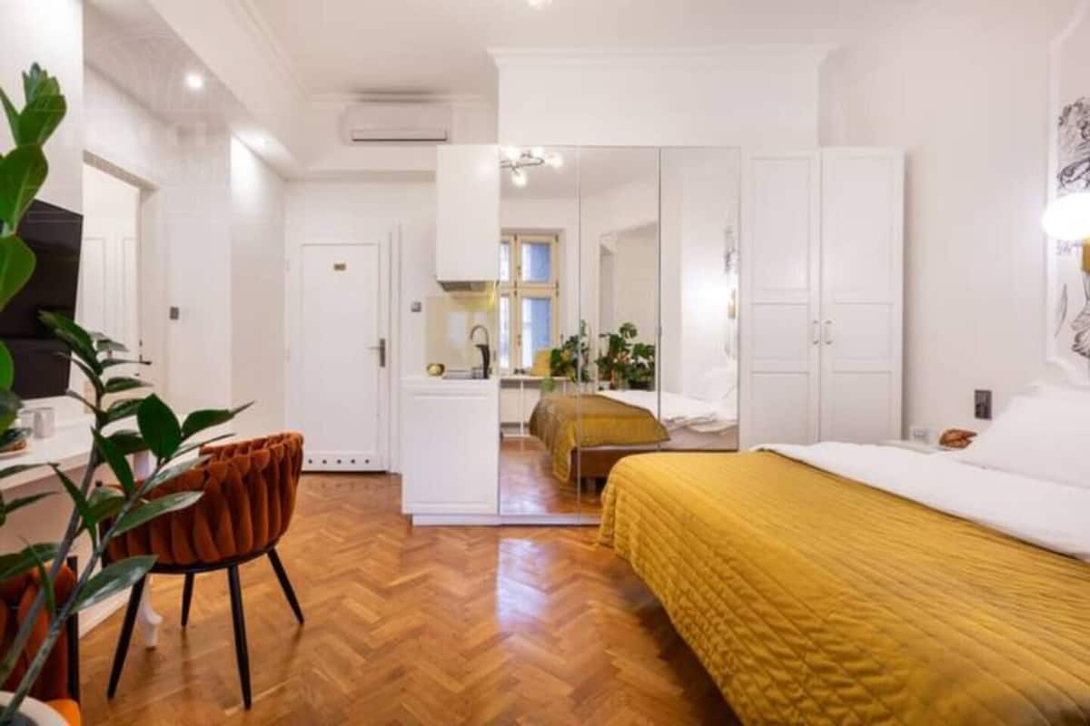 Ein Zimmer mit einem Bett, einem Sessel, einem Schreibtisch und einem Spiegel.