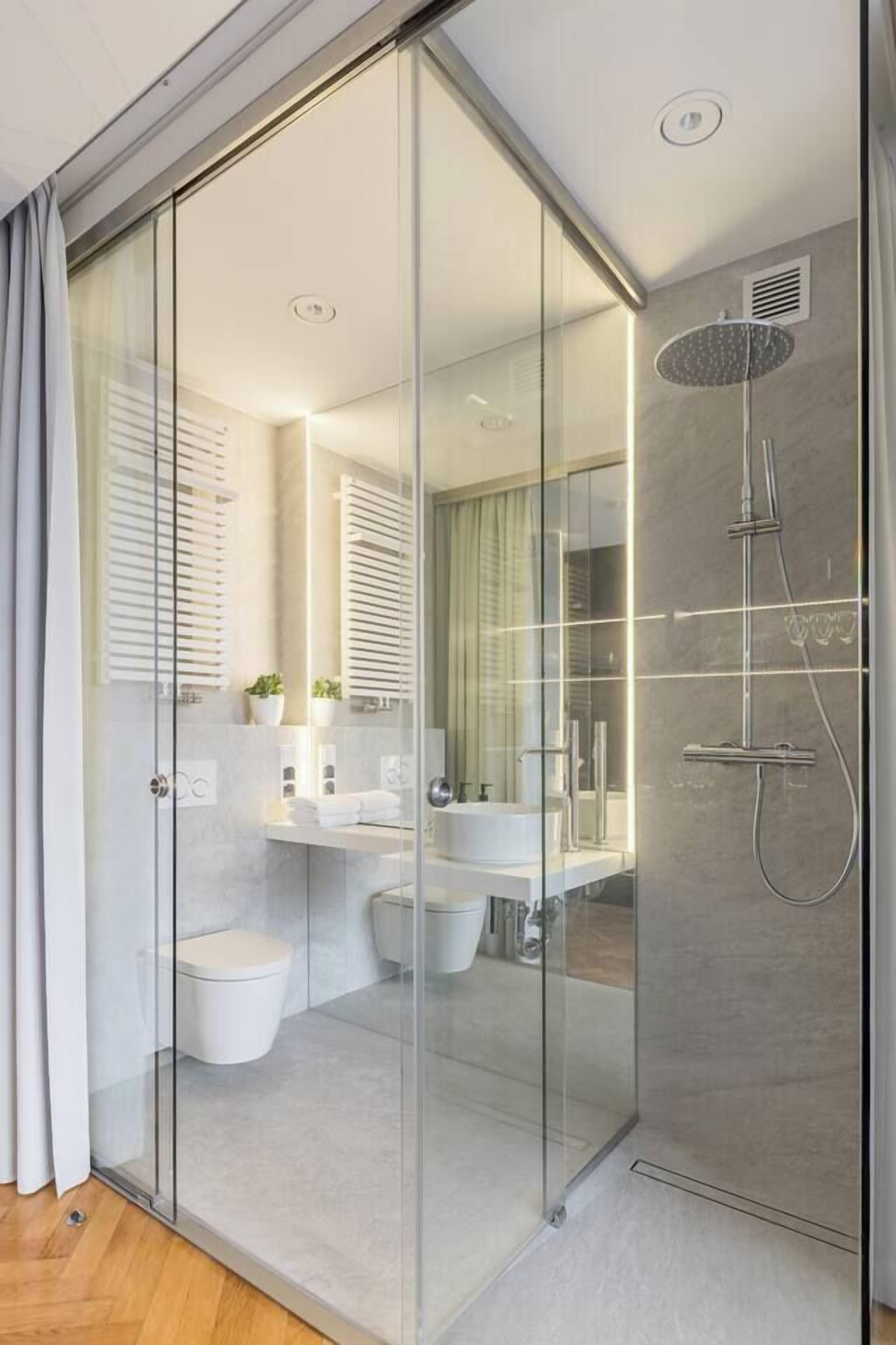 A modern bathroom with a glass shower enclosure, a toilet, and a sink.
