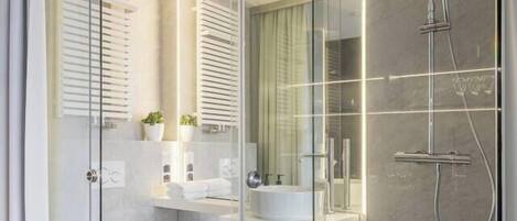 A modern bathroom with a glass shower enclosure, a toilet, and a sink.