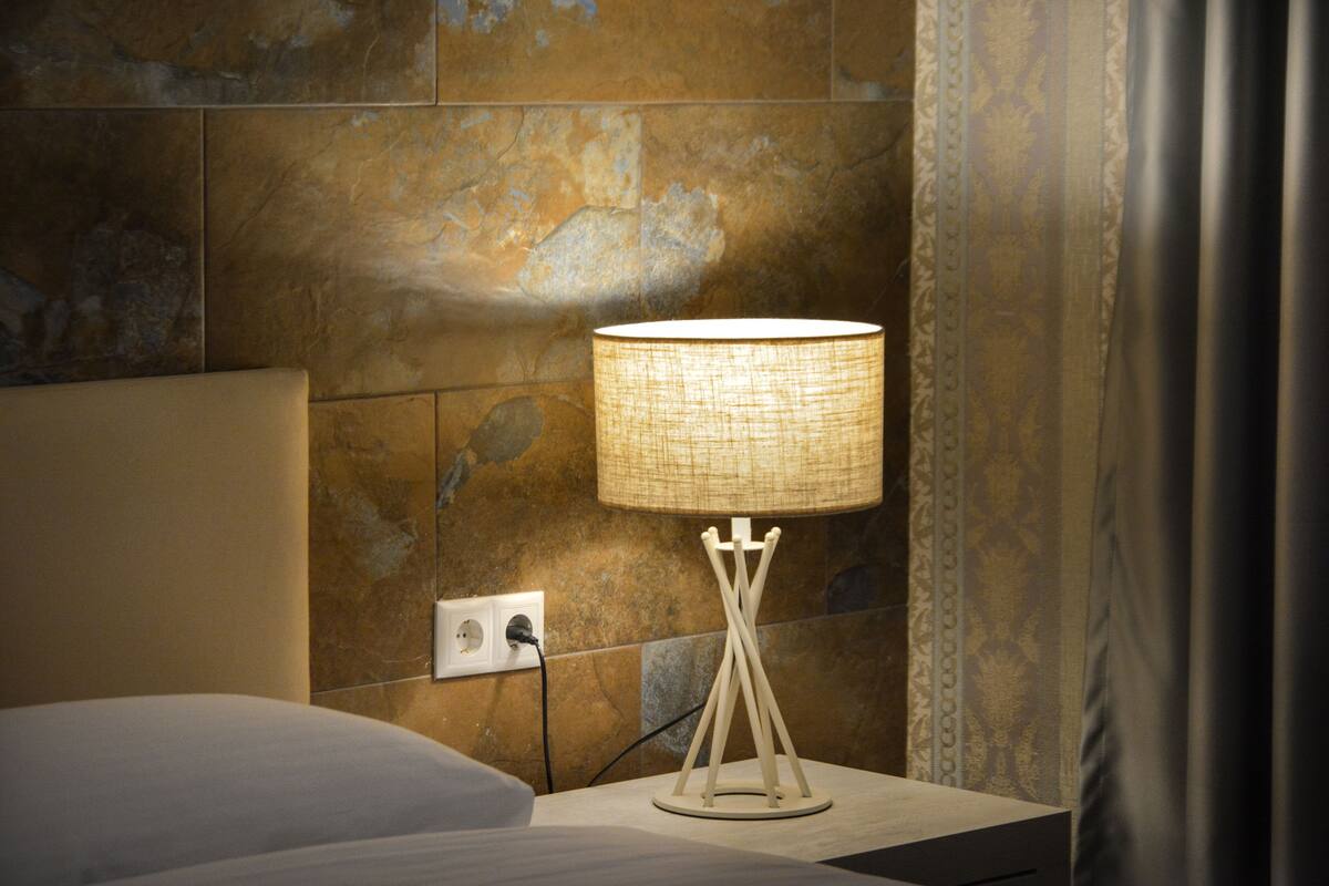 Een moderne badkamer met een marmeren wand, een nachtkastje met een lamp en een stopcontact.