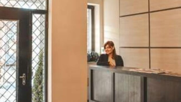 Un área de recepción con candelabro, una recepcionista y un diseño de interiores moderno.
