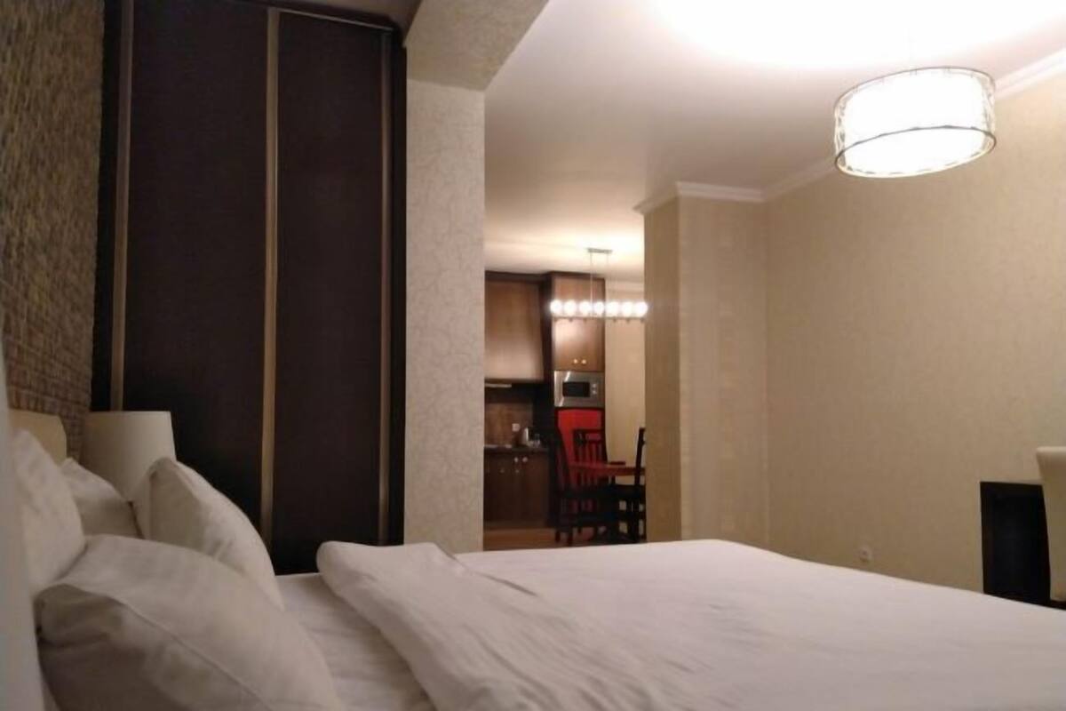 Een hotelkamer met een bed, een bureau en een kitchenette op de achtergrond.