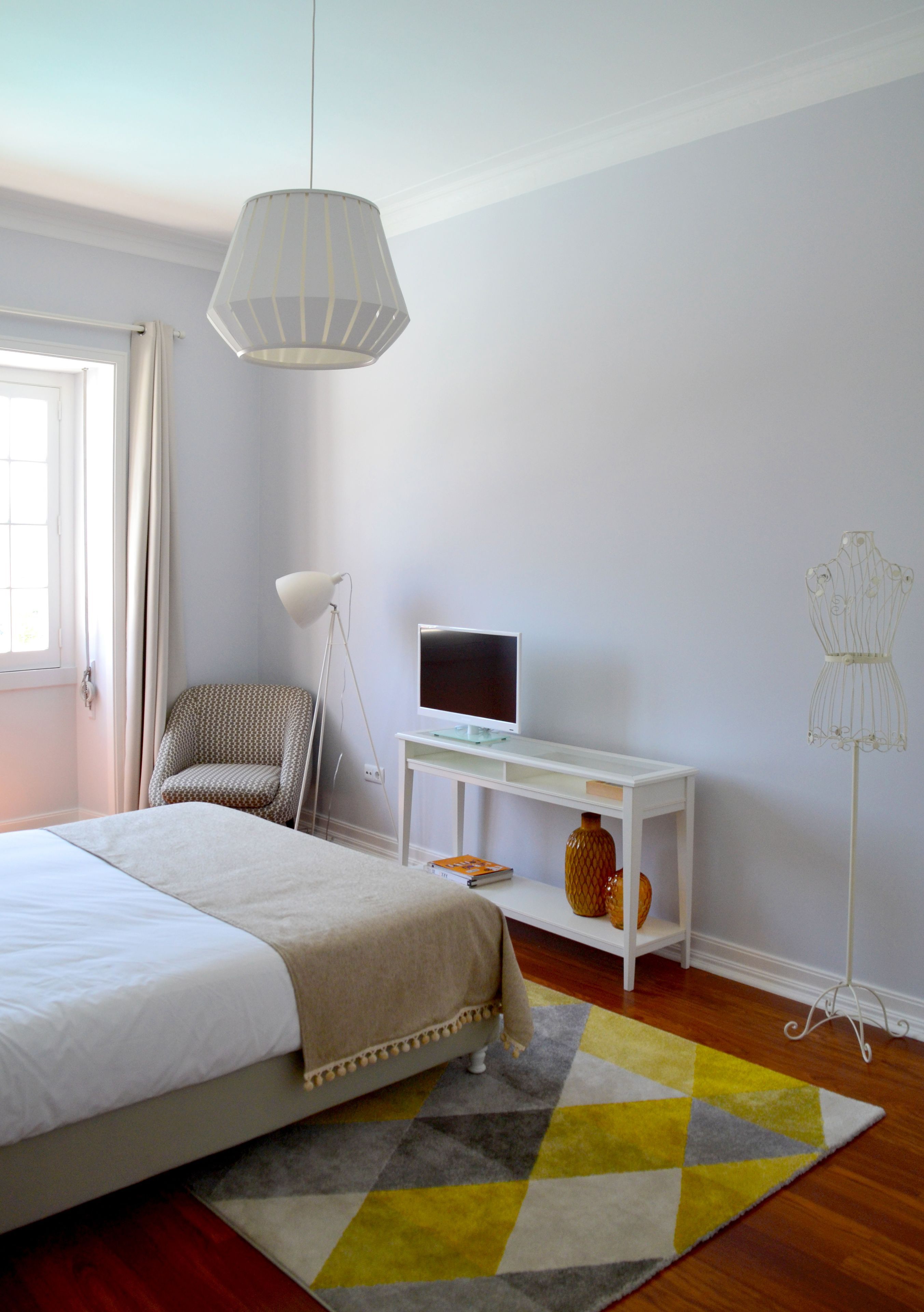 Un dormitorio con cama, escritorio, silla, lámpara de pie y un maniquí.