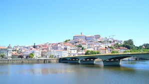 A bridge over a calm river with a cityscape in the background. - Archisuites (Coimbra)