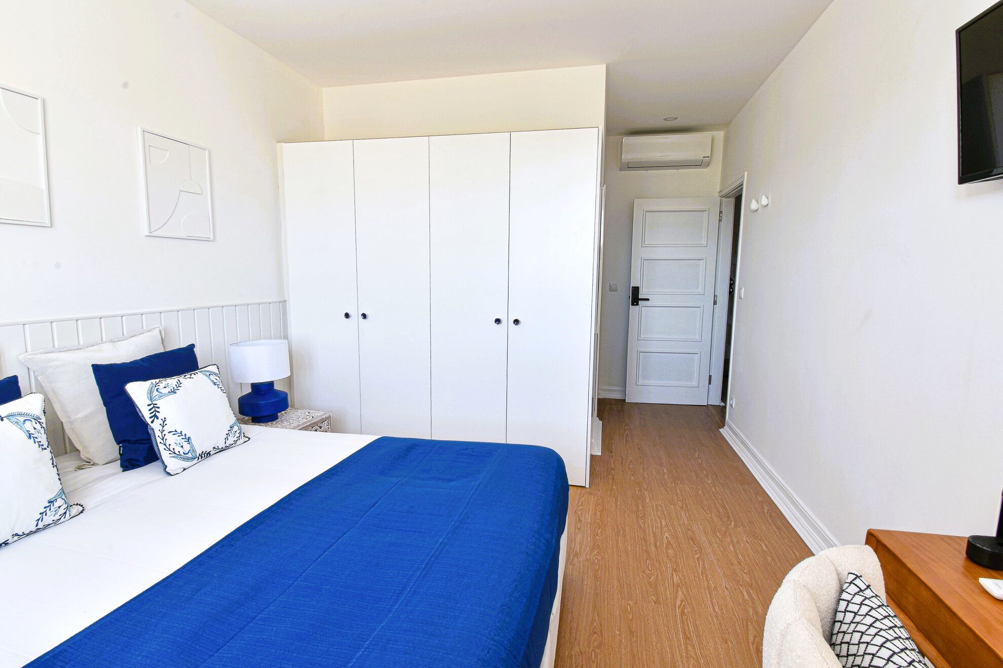 Une chambre à coucher avec un lit, une armoire, une table de chevet et une lampe.