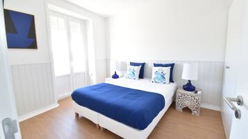 Un dormitorio con una cama grande, paredes blancas y una ventana.