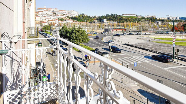 A balcony with a view of a cityscape, including a road with cars and a bridge. - Archisuites (Coimbra)