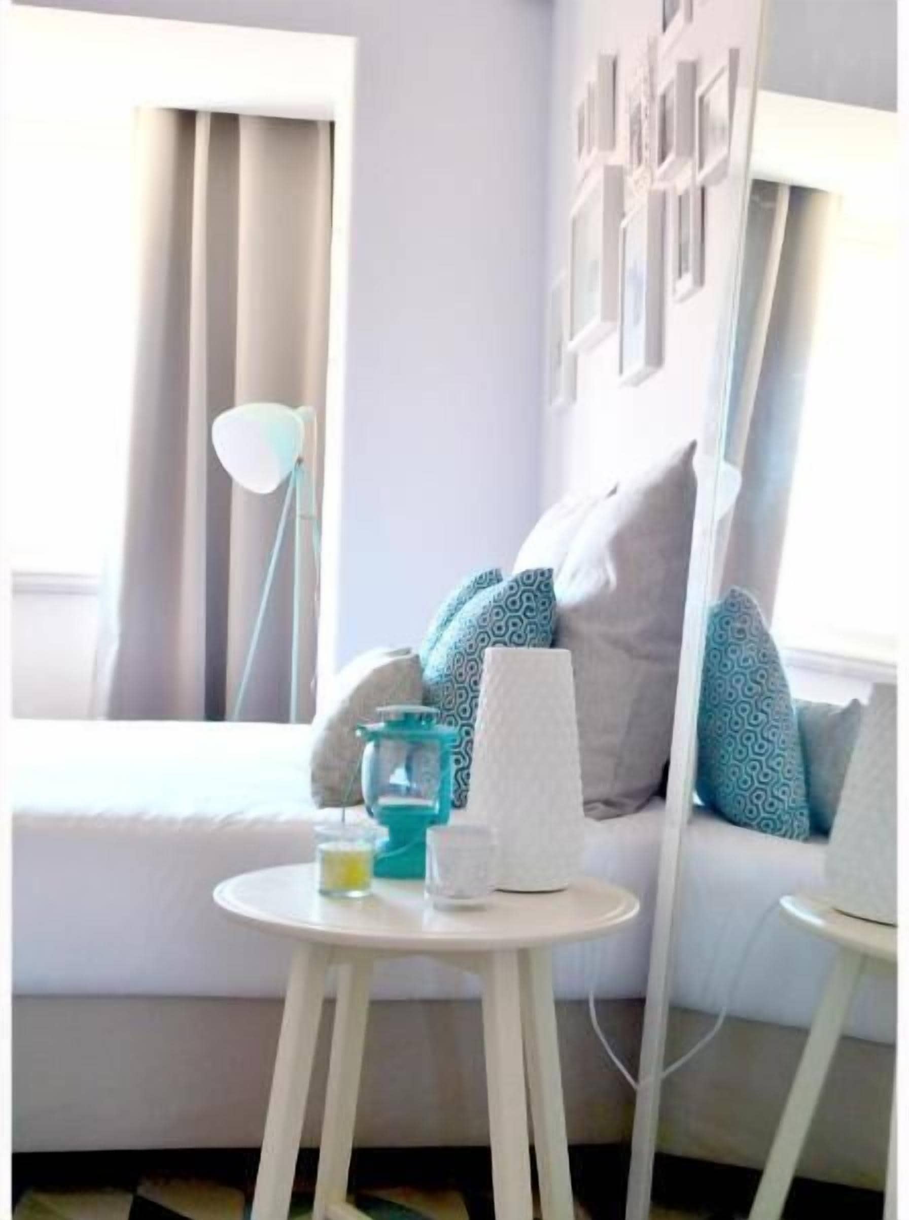 Une chambre d’hôtel avec un lit, une petite table ronde avec une lampe, une machine à café et une bouteille d’eau.