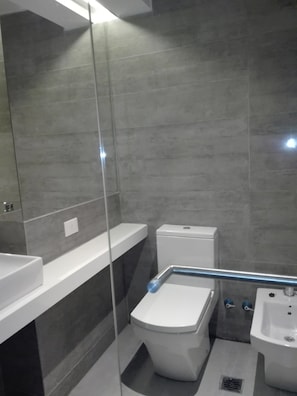 A modern bathroom with a toilet, bidet, and sink.