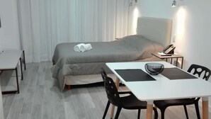 Ein Hotelzimmer mit Bett, Schreibtisch mit Stuhl, Telefon und Lampe.