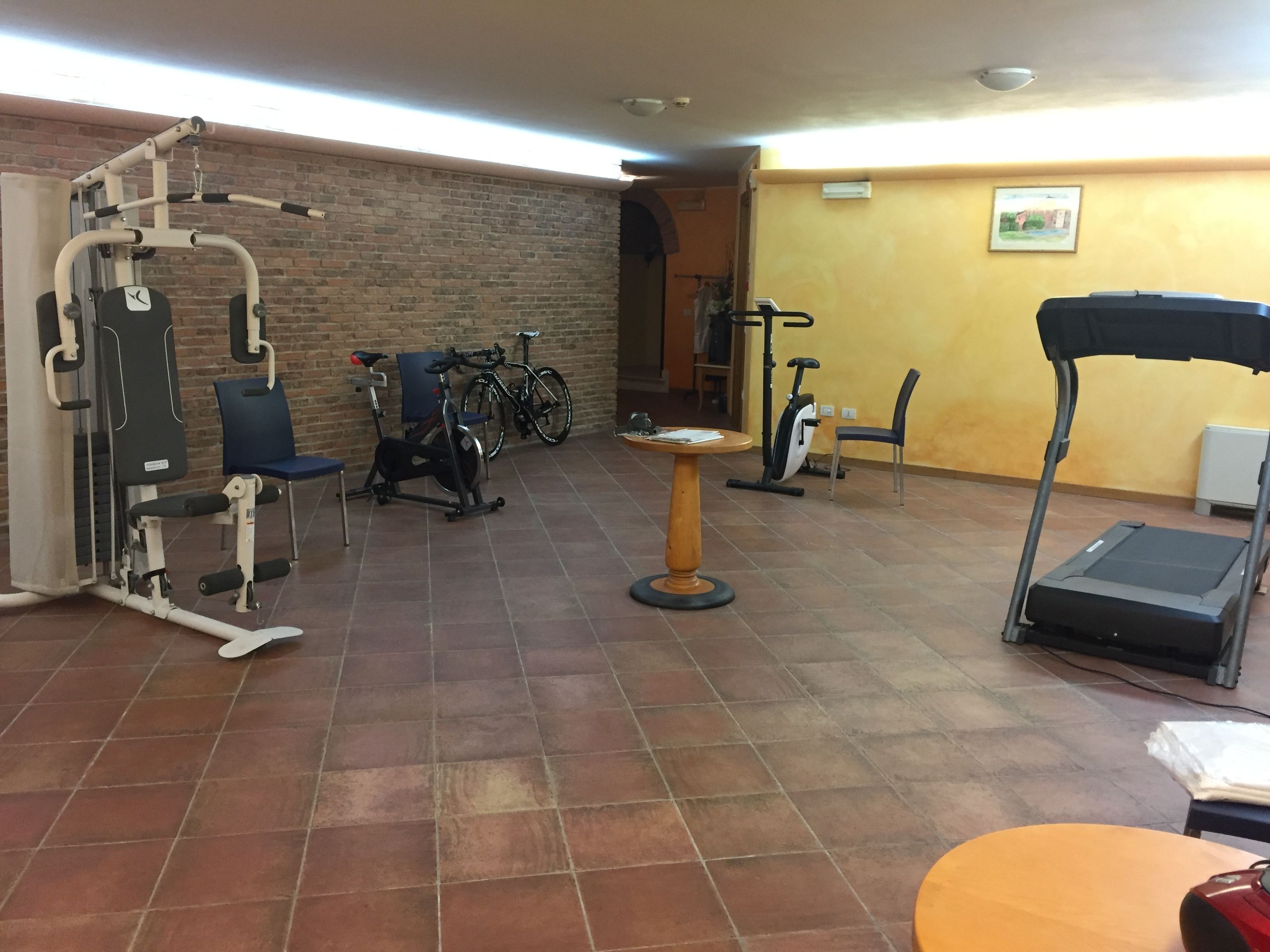 Uma academia com equipamentos de ginástica, esteira e uma cadeira.