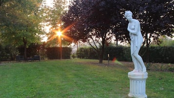 Een standbeeld in een park met een gazon en bomen.