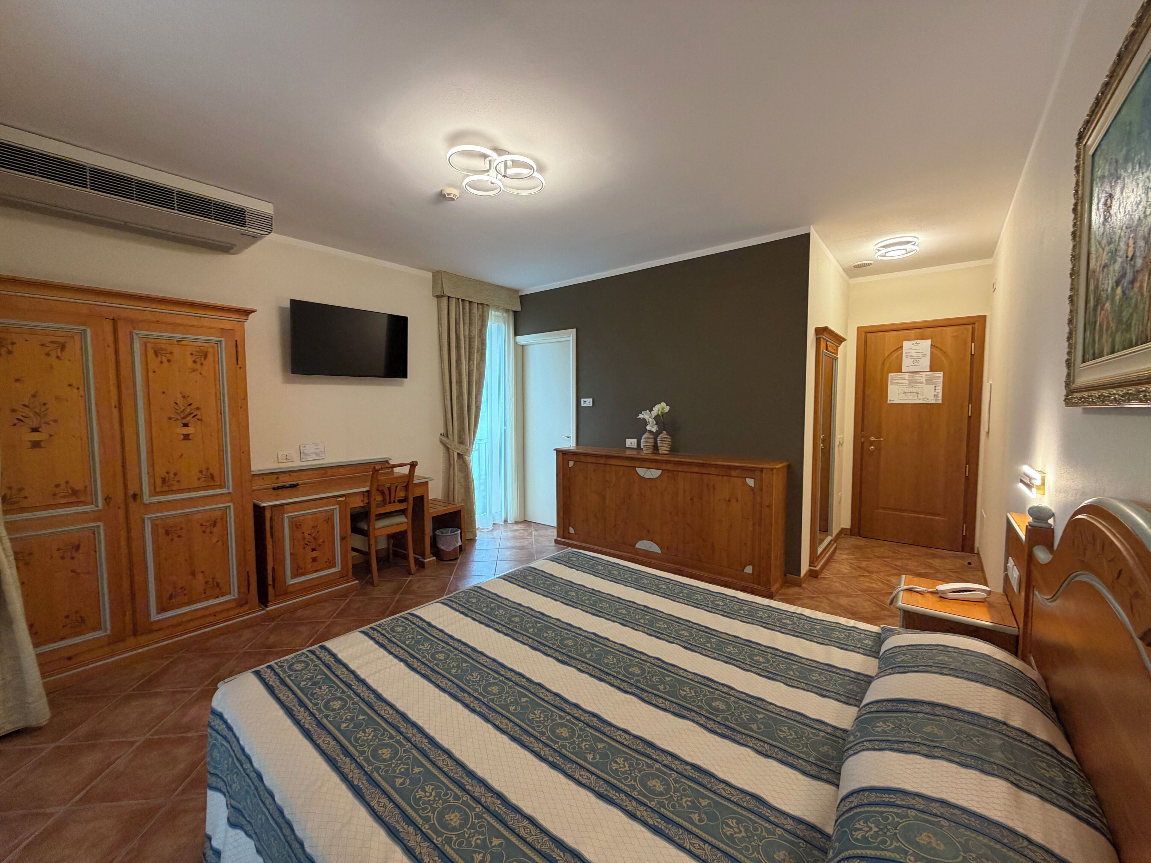 Ein Hotelzimmer mit Bett, Schreibtisch, Fernseher und Kleiderschrank.