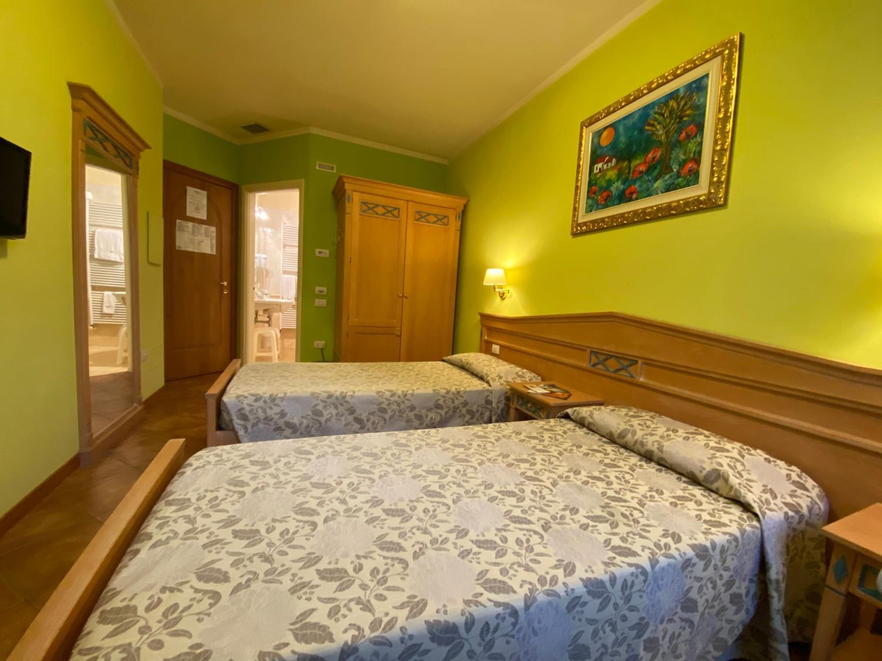 Una habitación de hotel con dos camas, un cabecero de madera, un cuadro en la pared y una puerta de madera.