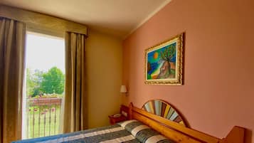 A hotel room with a bed, a painting on the wall, and a view of the outdoors.