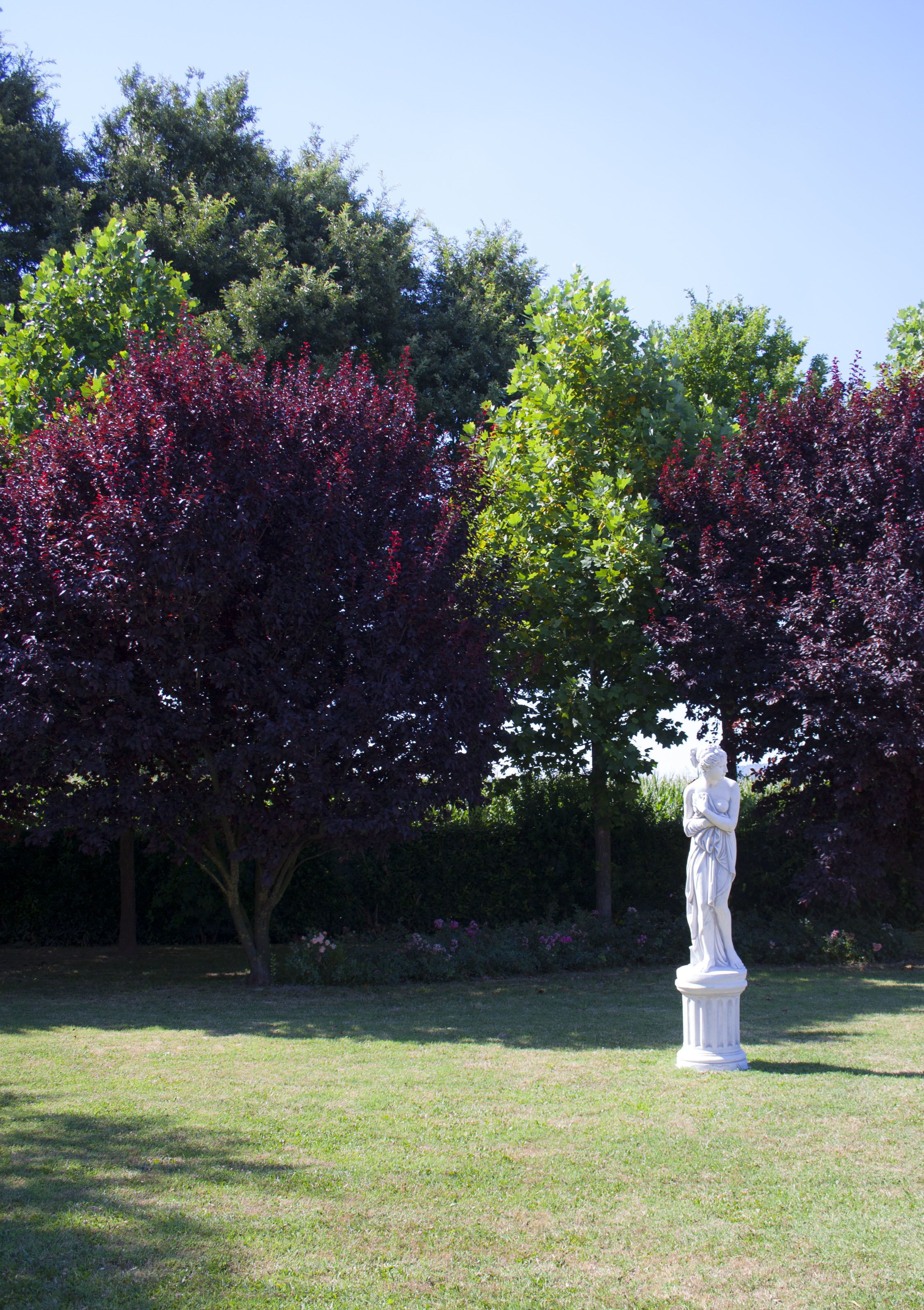 A statue in a garden with trees and grass.