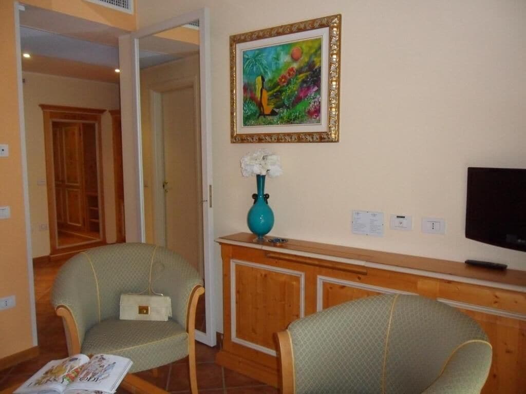 Une pièce comprenant deux fauteuils, un meuble en bois, un téléviseur et un tableau encadré accroché au mur.