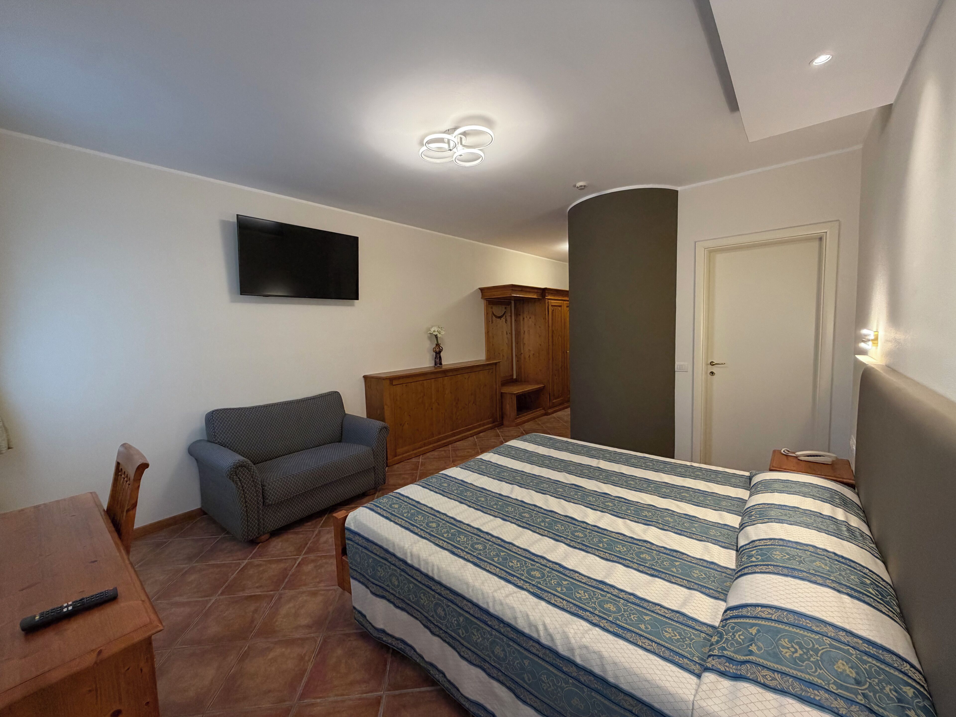 A bedroom with a bed, a sofa, a TV, a wardrobe, and a desk.