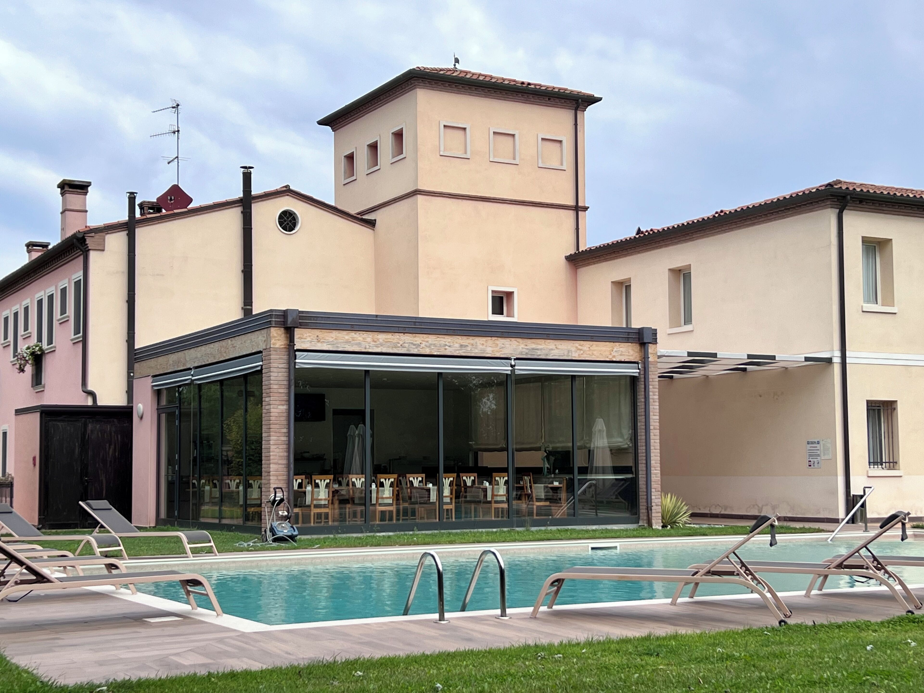 Un edificio moderno con piscina, mobiliario exterior y una terraza cubierta.
