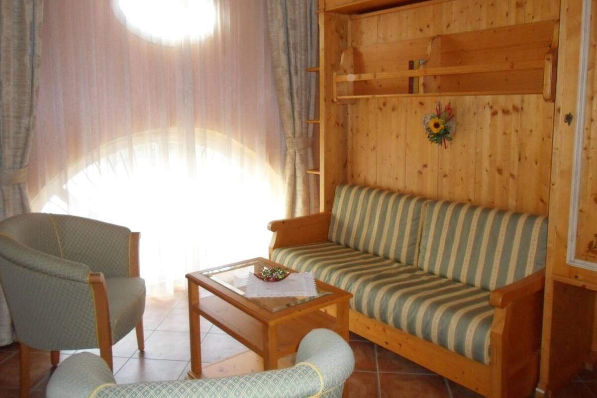 A cozy living room with a wooden sofa, a striped armchair, and a glass-top coffee table.