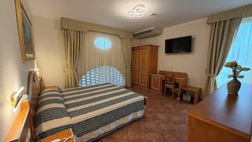 Een hotelkamer met een bed, een bureau, een televisie en een raam met gordijnen.