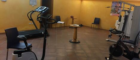 A gym with exercise equipment including a treadmill, stationary bike, and weight machines.