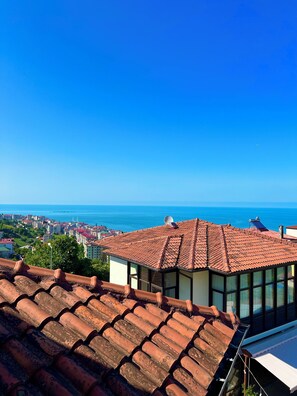 A building with a red-tiled roof and large windows overlooking a coastal cityscape. - Mehmet Efendi Konagi Otel Restaurant (Akçaabat)
