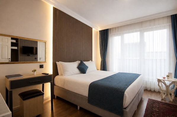 A hotel room with a bed, bedside table, desk, chair, and a television on the wall. - Genius Hotel Istanbul (Istanbul)
