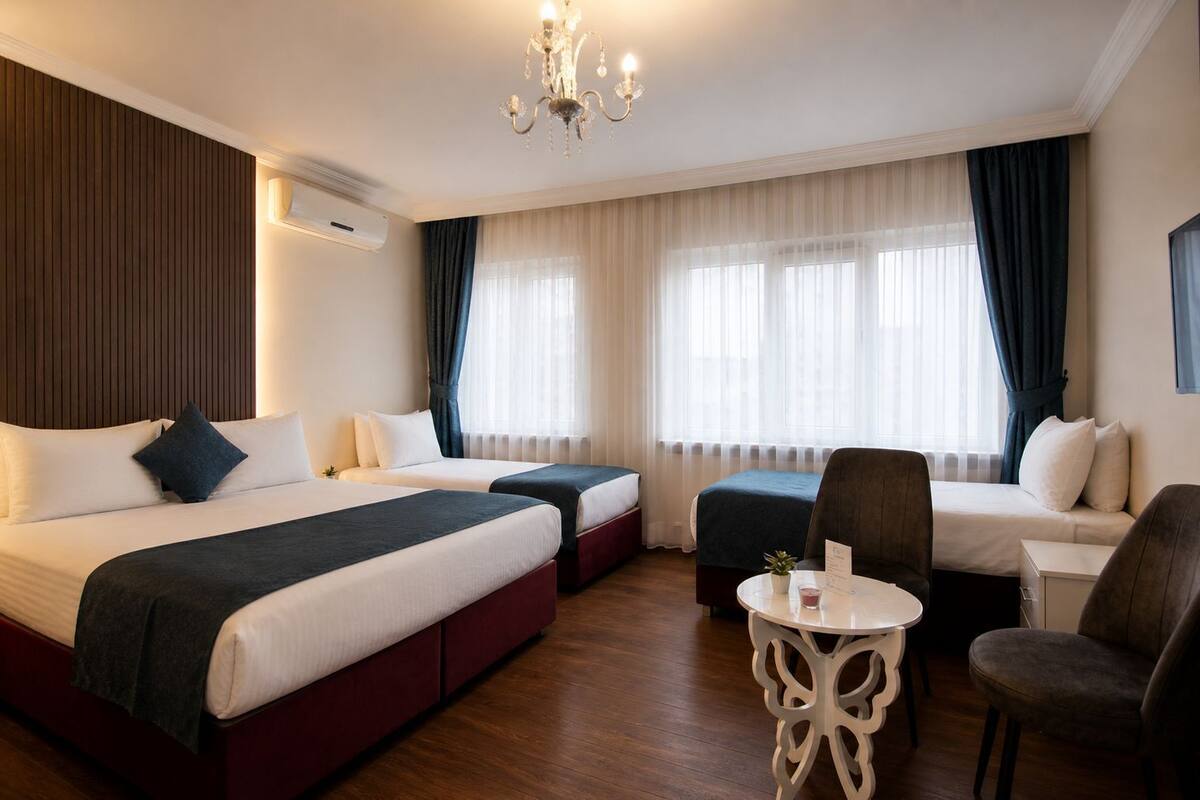 Une chambre d’hôtel avec deux lits, une petite table, une chaise et un lustre.