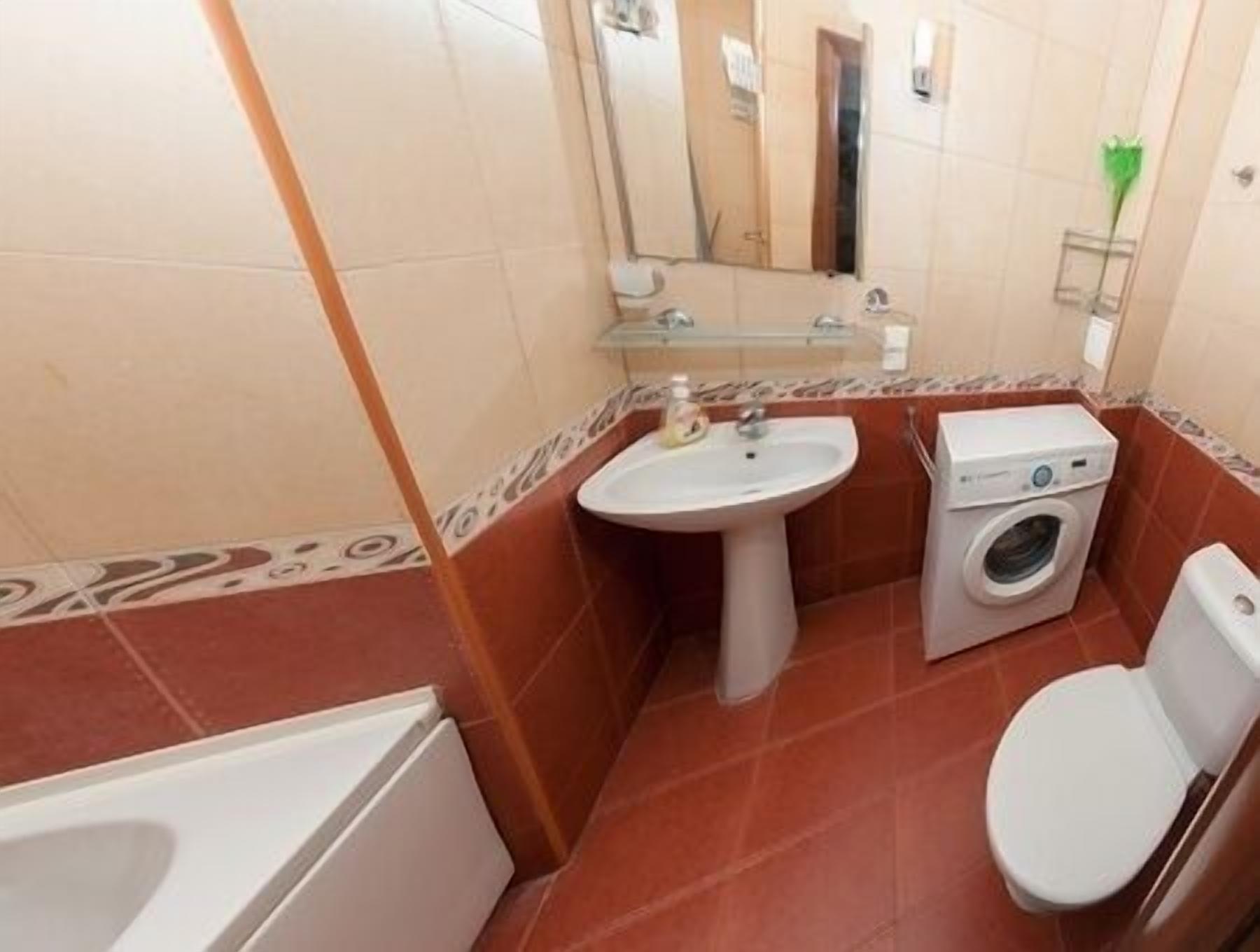 A compact bathroom with a sink, washing machine, toilet, and bathtub.