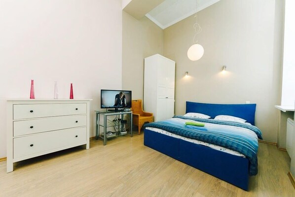 A bedroom with a bed, a dresser, a television, and a chair.