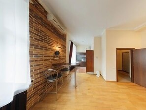 A modern kitchen with a brick wall, a dining area with a chair, and a wooden floor. - Hotrent Olympic (Kyiv)