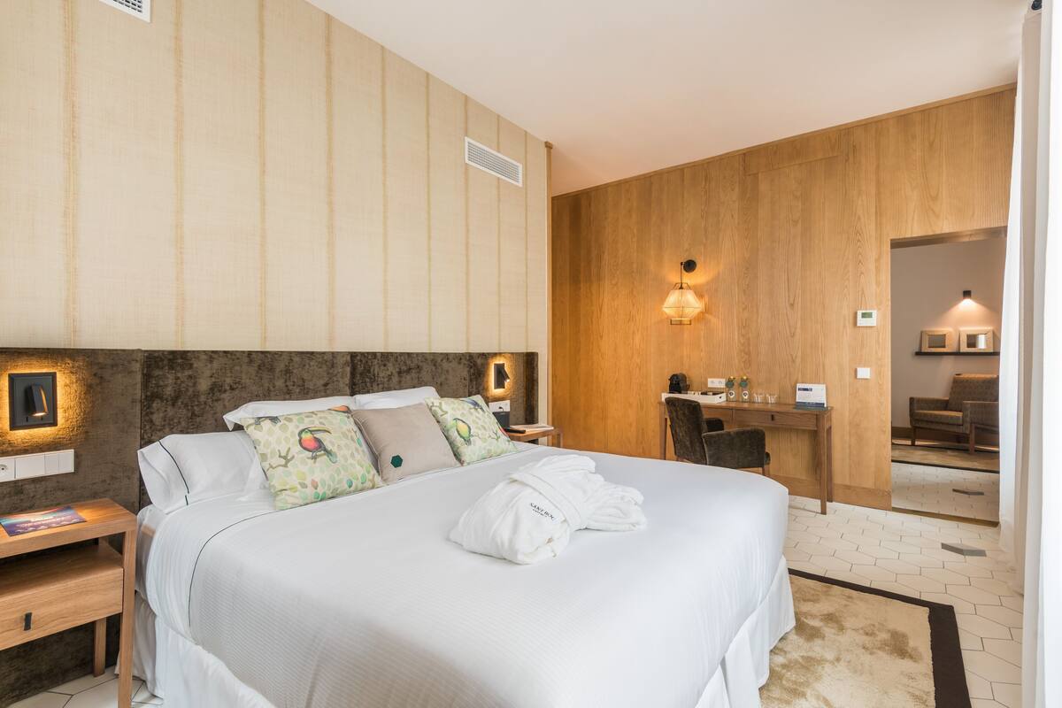 A hotel room with a large bed, a desk, and a chair.