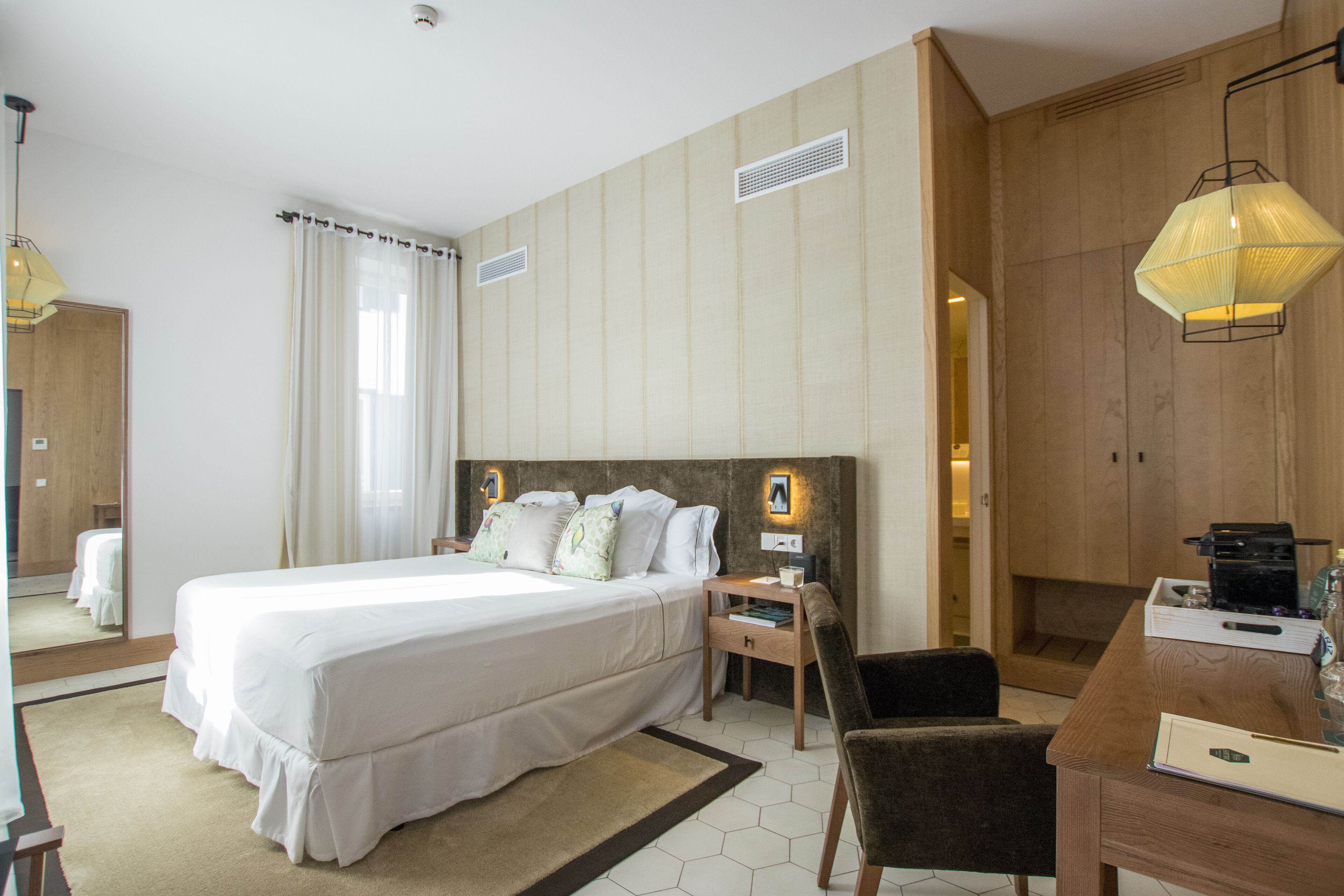 Une chambre d’hôtel avec un grand lit, des tables de chevet, un bureau et une chaise.