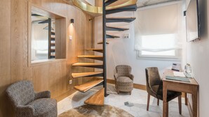 A modern interior with a spiral staircase, wooden walls, and a seating area with a table and chairs. - Boutique Hotel Sant Roc & Spa (Mahón)