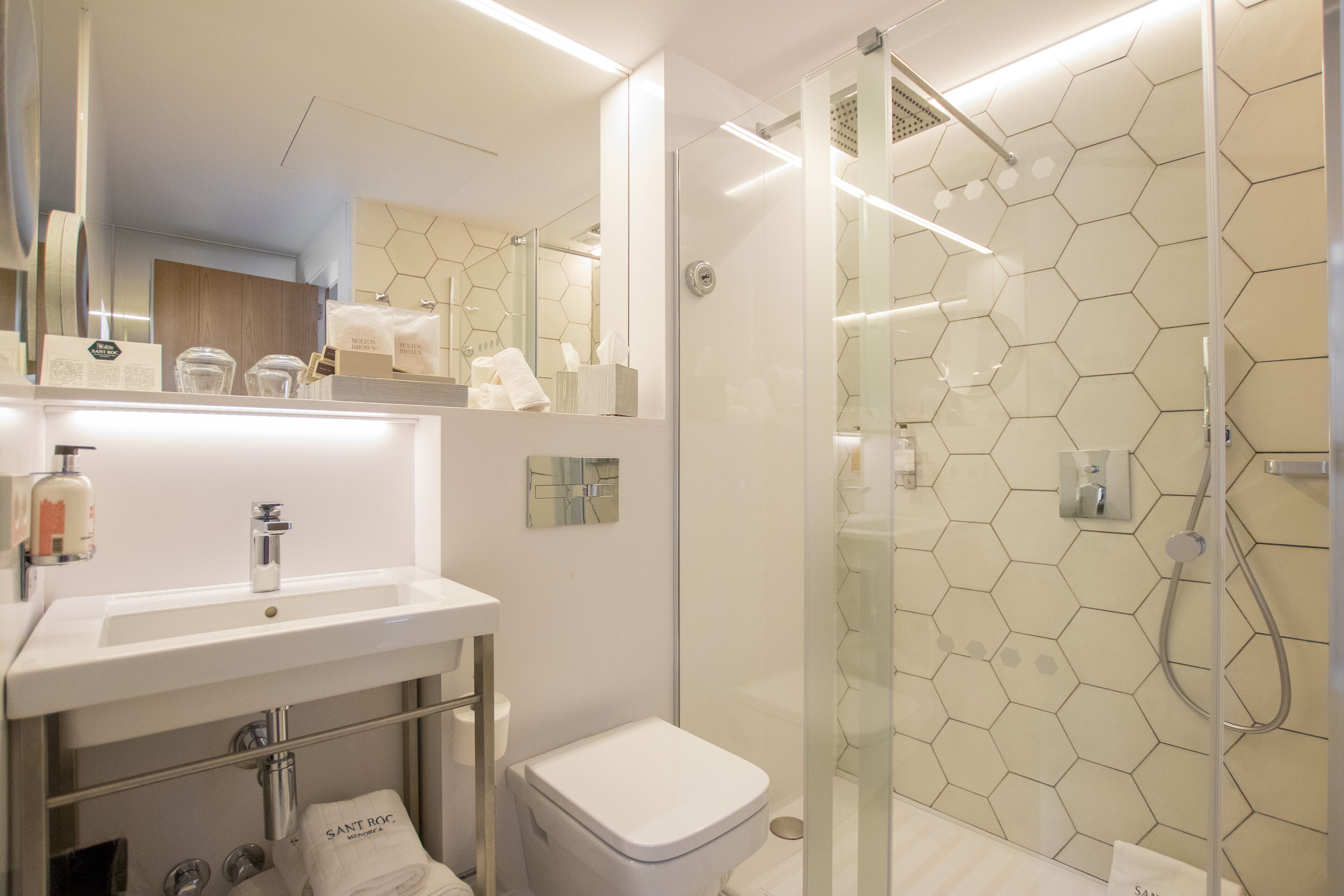 A modern bathroom with a glass-enclosed shower, a white sink, and a toilet.