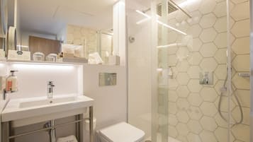 Un baño moderno con ducha de vidrio, lavamanos blanco y retrete.