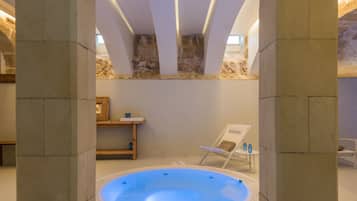 Un área de spa con hidromasaje, paredes de piedra y un banco de madera.